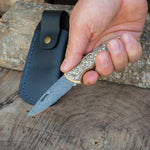 El işçiliğiyle Yatağan’da üretilmiş, kısa boyutlu ve fonksiyonel Damascus çelik katlanır bıçak; pirinç sapında gravür detaylar barındırır